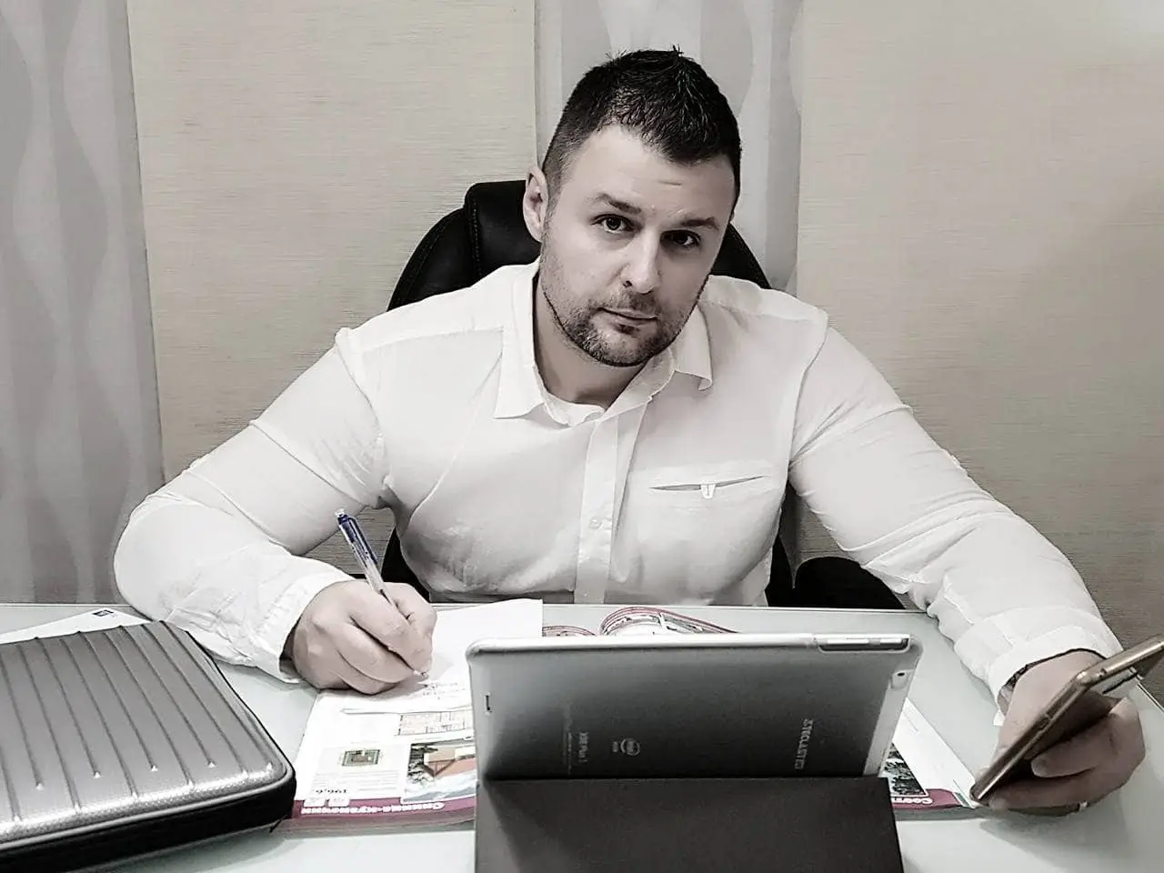 Muškarac radi na tabletu i telefonu u uredu, fokusiran na posao.